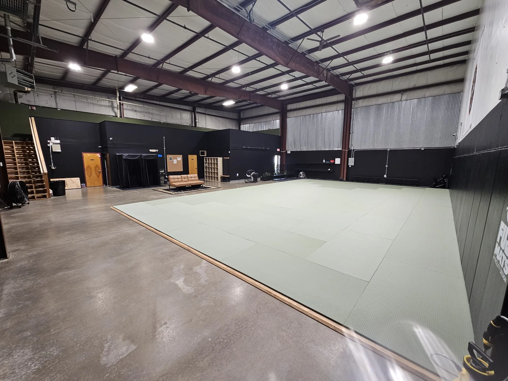 Arete academy floor — mats, belt display, and lounge